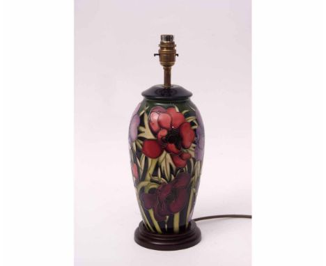 Moorcroft lamp base with a stylised tube lined design of anemones or hibiscus on a black oval base, 30cms high  