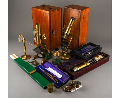 A box containing a collection of scientific instruments, including two late 19th/ early 20th century brass monocular microsco