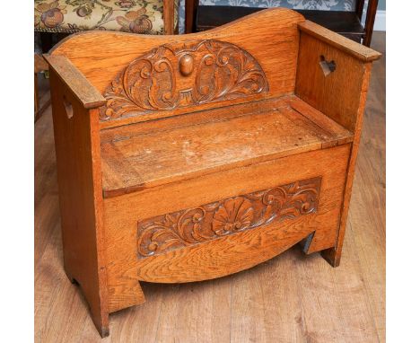 An Arts &amp; Crafts style oak Monk`s bench \ hall bench, curved back rail with central fan shaped carved foliate decoration,
