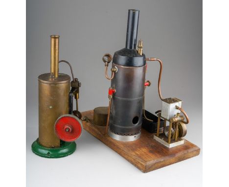 A Burnac Product vertical copper steam engine, powering a flywheel and single cylinder, on a green painted cast metal base wi