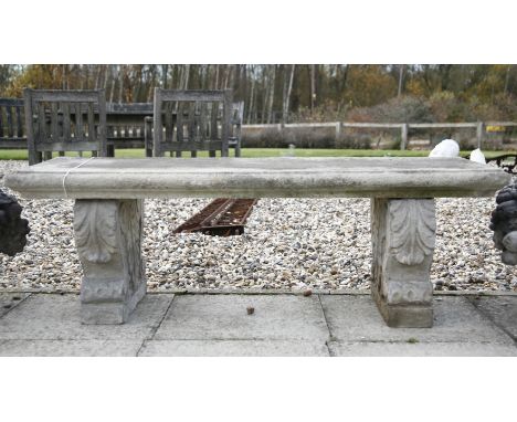 A reconstituted stone garden bench, the rectangular seat on acanthus decorated end supports, 124 cm x 42 cm x 40 cm