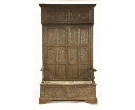 An oak bacon settle,18th century and later, profusely carved with stylised leaves and flowers, the cornice over two doors, ab