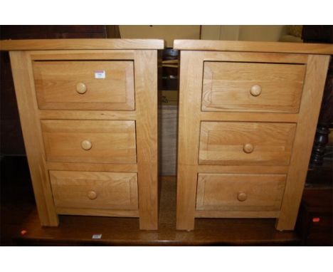 A pair of good quality light oak three drawer bedside chests 