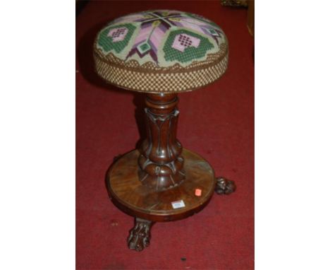 A Victorian mahogany and tapestry upholstered revolving piano stool, raised on paw feet