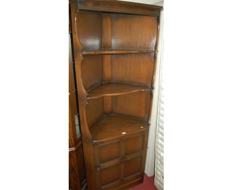 An Ercol dark elm freestanding corner cupboard, having shelved upper section 