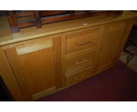A good quality joined light oak sideboard having three central drawers flanked by cupboard doors