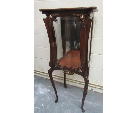 A late 19c mahogany Art Nouveau vitrine cabinet on stand, the mirrorback windowed cabinet with ormolu figurative enamel mount