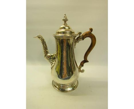 An early Victorian silver coffee pot of baluster form with carved wood scrolling handle, having a hinged dome cover with fini