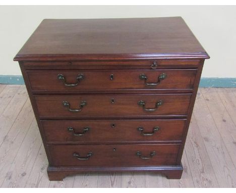 A George III mahogany chest of small proportion having four long graduated drawers together with a slide and supported on bra