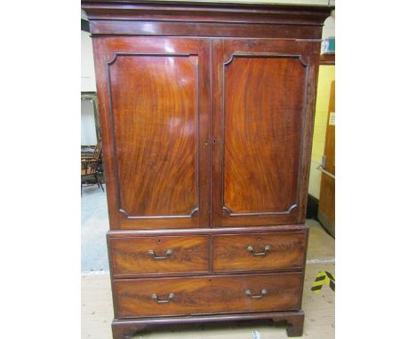 A late Georgian figure mahogany linen press fitted with five pull out drawers enclosed by two panelled doors under a moulded 