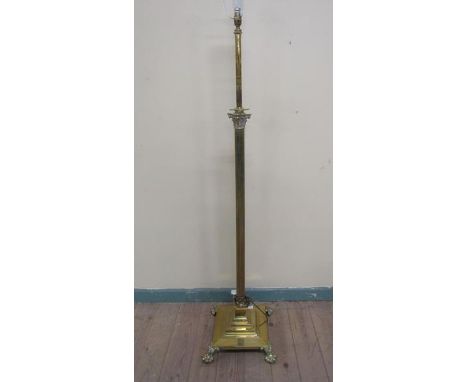 A late 19c/early 20c brass Corinthian column lamp stand of adjustable height supported on a stepped square base with bold lio