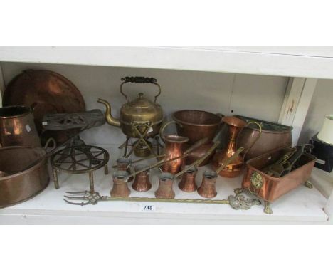 A shelf of assorted brass and copper including kettle with burner and trivet, measures etc.