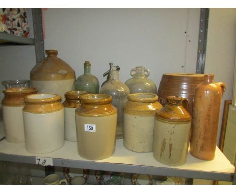 A shelf of stoneware and glass bottles including flaggons, soda syphons etc.