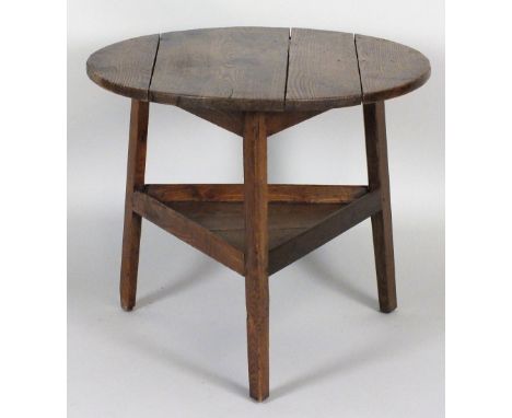 A George III elm cricket table, the four plank circular top on three splay legs united by a galleried shelf stretcher, 71cm d