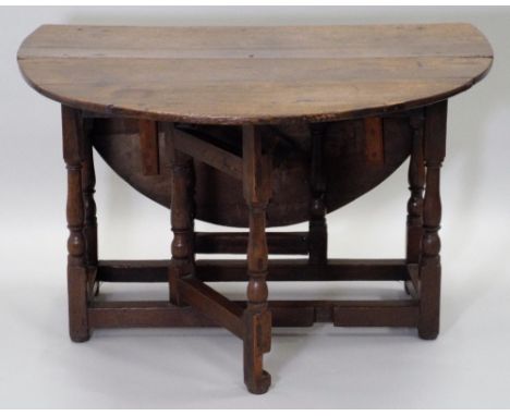 An early 18th century oak gate-leg breakfast table, the oval top over two relined end frieze drawers, on eight turned baluste