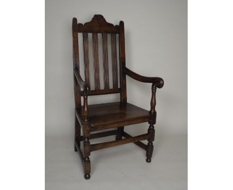 A late 17th century Welsh oak open armchair, the arched top rail over four lath line mounded back above a three board seat be