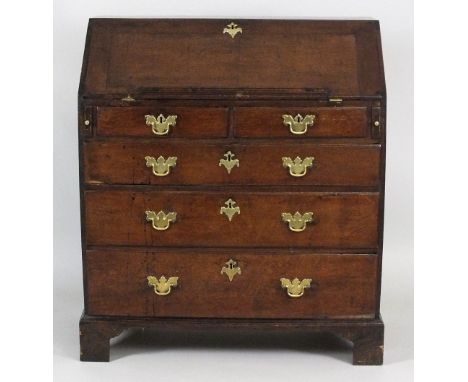 A George III oak fall front bureau the fall opening to reveal six pigeon holes and four short drawers over two short and thre