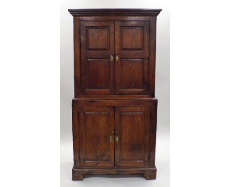 An 18th century joined oak food cupboard, the ogee moulded cornice over two panel fielded cabinet doors to the top section an