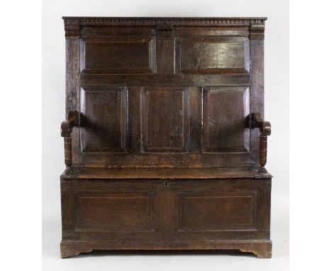 An 18th century joined oak box seat settle, the dentil moulded top rail over five rectangular fielded panels between open arm
