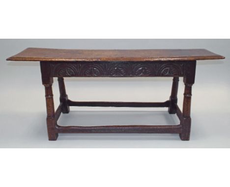 A 17th century and later joined oak bench, the single plank seat with moulded edge, over a lunette carved frieze, on four rin