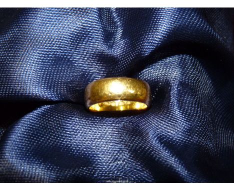 A 22ct gold wide Wedding band, smaller than a K size, weight 6.9g.