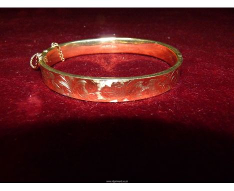 A Birmingham 9ct gold, yellow gold half engraved hinged bangle with safety chains (damaged), maker Payton, Pepper and & Sons 