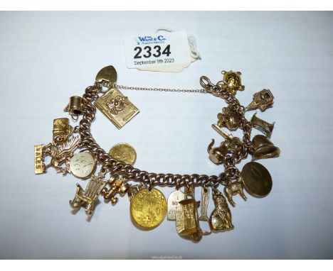 A 9ct gold charm bracelet with heart locket fastenings with 9ct gold yellow gold charms including tractor, watering can, pram