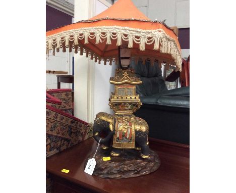 Indian elephant porcelain table lamp on carved wooden base with shade and artificial flowers in flower pot