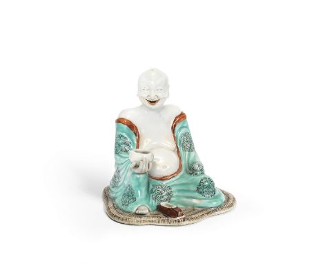 An unusual enamelled export figure of Budai18th centurySeated on a simulated woven reed mat, holding a shallow bowl, the robe