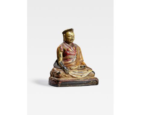 A POLYCHROMED BLACK STONE FIGURE OF A GELUG LAMATibet, circa 16th centuryThe lama carved from heavy stone, wearing a thick me
