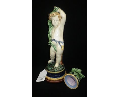 A MINTON MAJOLICA CANDLESTICK in the form of a boy holding rushes above his head