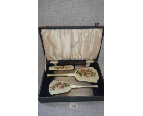 A DRESSING TABLE SET comprising of two brushes, a mirror and a comb, decorated with cream guilloche enamel and floral sprays,