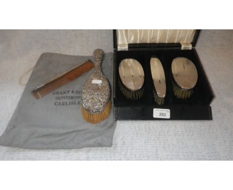 A SET OF THREE SILVER-BACKED BRUSHES in a fitted presentation case and an embossed silver hairbrush and comb 