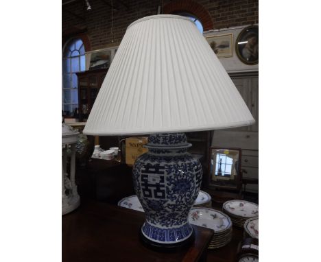 A TABLE LAMP IN THE FORM OF AN ORIENTAL BLUE AND WHITE COVERED VASE with a white pleated shade 