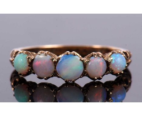 A five stone opal ring, the round graduated opal cabochons claw mounted to shaped shoulders and plain band stamped 375, hallm