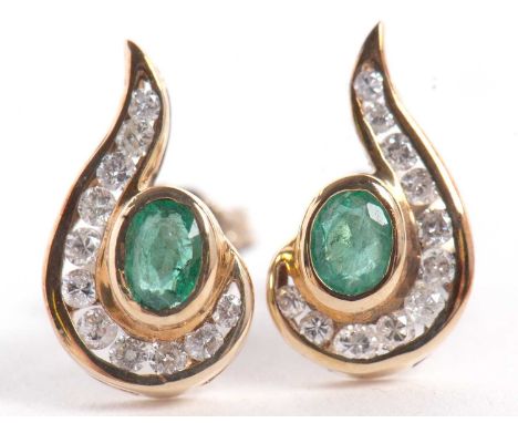 A pair of 9ct emerald and diamond earrings, the central collet mounted oval emerald, half surrounded with a sweep of channel 