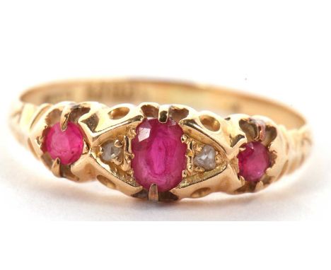 An 18ct ruby and diamond ring, the central oval ruby set to either side with diamond hightlights and a further round ruby to 