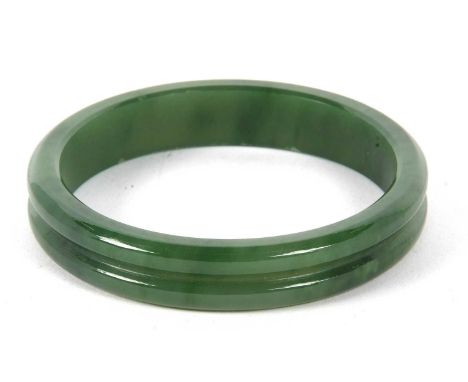 A nephrite bangle, the 14mm wide bangle with a central carved groove, inner diameter, 6.5cm, 51gGood condition with very ligh