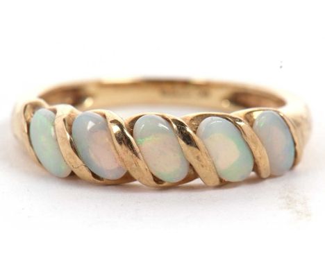 A 9ct opal ring, the five oval opal cabochons set at a 45° angle with a twist of gold separting each, with plain band hallmar