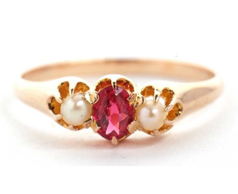 A 14k ruby and cultured pearl ring, the oval ruby set to either side with a cultured pearl, all claw mounted to a plain band 