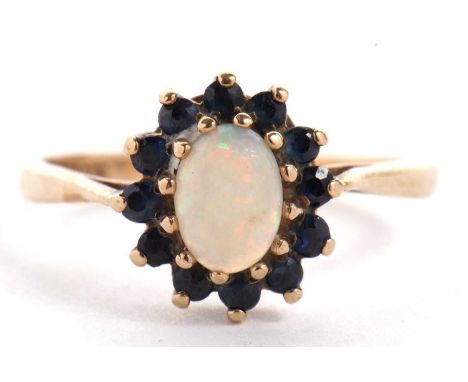 A 9ct sapphire and opal cluster ring, the central oval opal cabochon surrounded by small round sapphires, all claw mounted to