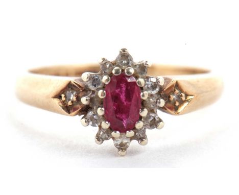 A 9ct ruby and diamond ring, the central oval ruby surrounded by small round diamonds, with diamond highlight to shoulders an