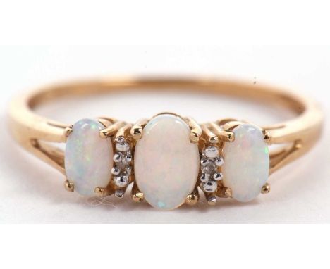 A 9ct opal and diamond ring, the three slightly graduated oval opal cabochons interspaced with a small round diamond, with sp