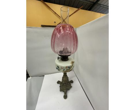 A BRASS OIL LAMP WITH DECORATIVE RESRVOIR, GLASS FUNNEL AND CRANBERRY GLASS SHADE 
