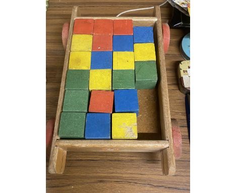 A VINTAGE CHILD'S WOODEN PULL ALONG CART CONTAINING COLOURED WOODEN BRICKS 