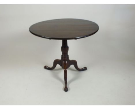 A late George III oak tripod table, the circular plank top on a later block and pilaster column, three downcurved tapering le