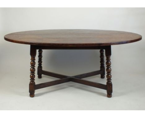 A Titchmarsh and Goodwin oval oak dining table, the planked top on a plain frieze and bobbin turned and block legs, joined by