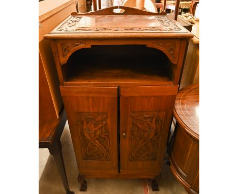 An Indonesian carved hardwood side cabinet with open shelf and two doors enclosing slides, on cabriole supports, 60 cm wide x