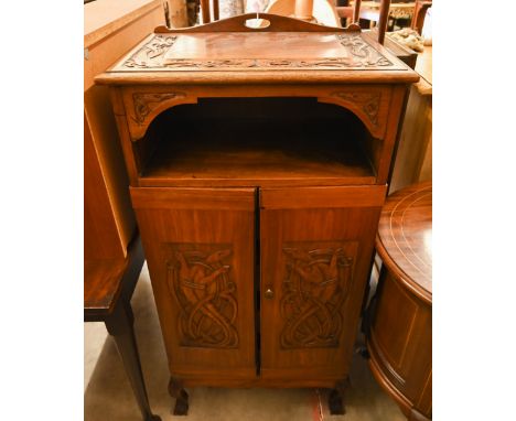 An Indonesian carved hardwood side cabinet with open shelf and two doors enclosing slides, on cabriole supports, 60 cm wide x