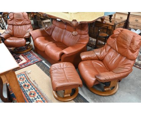 An Ekornes Stressless tan leather suite comprising two seater sofa, pair of reclining armchairs and footstool 